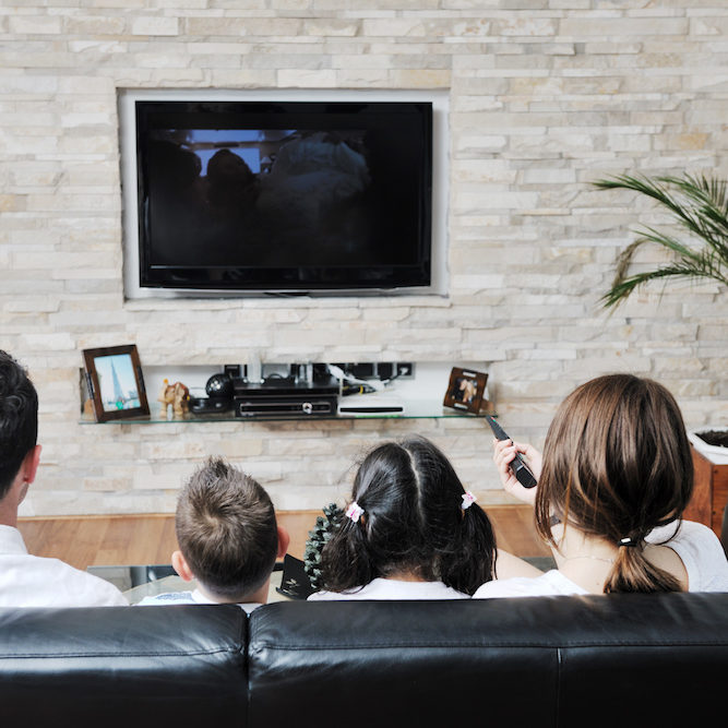 happy young family wathching flat tv at modern home indoor